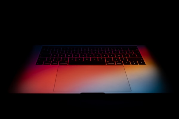 Late night photograph of Apple Macbook Pro with colorful wallpaper.