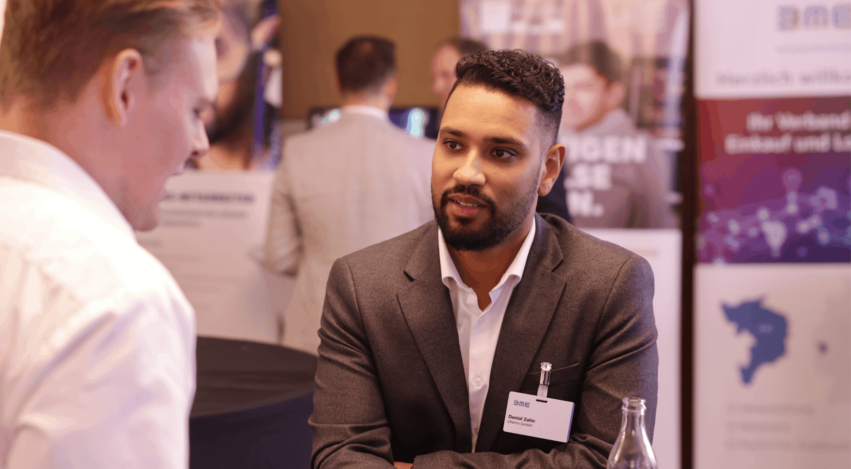 Geschäftsmann mit Namensschild im Gespräch mit einer anderen Person auf einer Konferenz oder Messe.